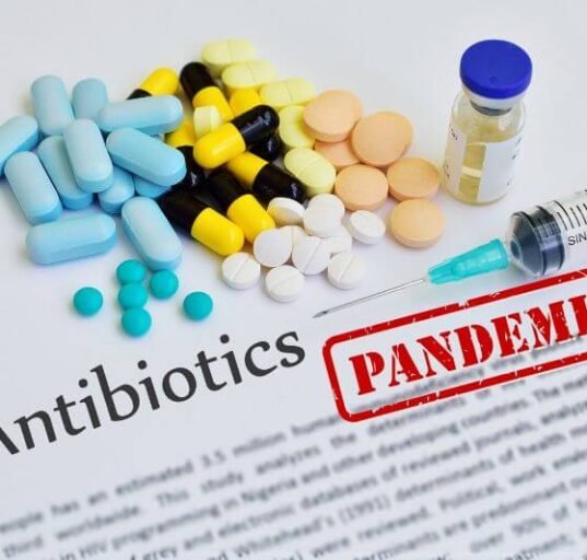 Assorted antibiotics and syringe on document labeled pandemic, illustrating the threat of antibiotic resistance