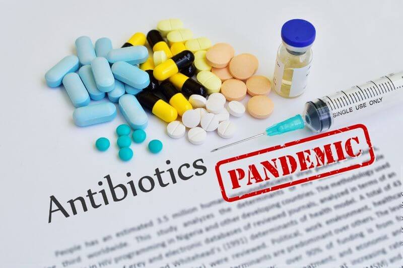 Assorted antibiotics and syringe on document labeled pandemic, illustrating the threat of antibiotic resistance