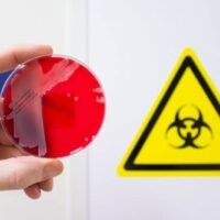 Lab-made pathogens being handled in a biohazard facility with synthetic virus sample in petri dish