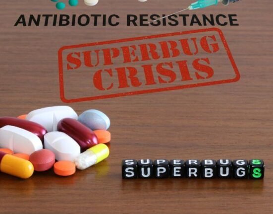 Realistic image showing medical supplies on a wooden surface with bold text "ANTIBIOTIC RESISTANCE", illustrating the superbug crisis.